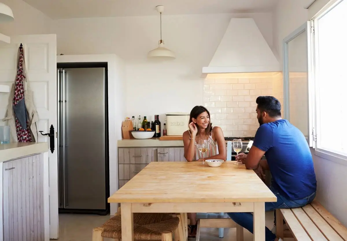 Adult couple talk and drink wine in the kitchen, copy space